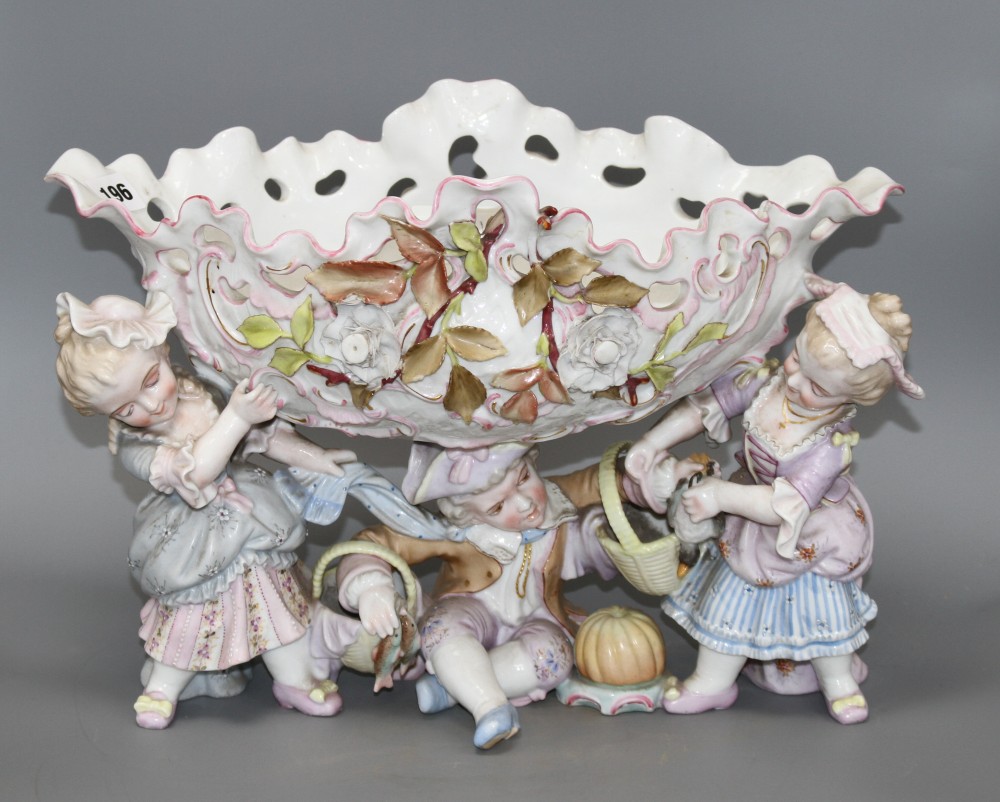 An early 20th century German porcelain centrepiece, with floral encrusted bowl supported by three children, height 28.5cm, width 44cm